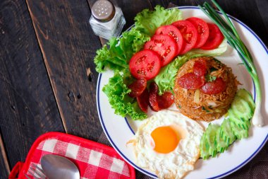 Kızarmış pilav ve Çin sosisi kızarmış yumurta, domates ve marul ile servis edilir..