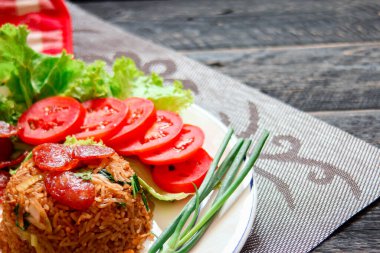 Kızarmış pilav ve Çin sosisi kızarmış yumurta, domates ve marul ile servis edilir..