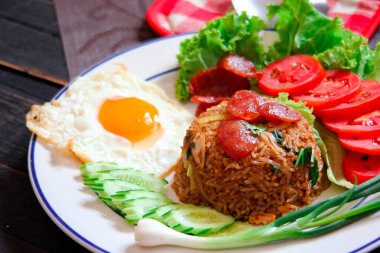 Kızarmış pilav ve Çin sosisi kızarmış yumurta, domates ve marul ile servis edilir..