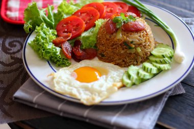 Kızarmış pilav ve Çin sosisi kızarmış yumurta, domates ve marul ile servis edilir..