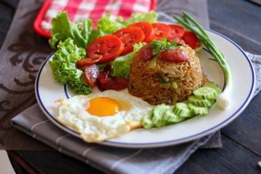 Kızarmış pilav ve Çin sosisi kızarmış yumurta, domates ve marul ile servis edilir..