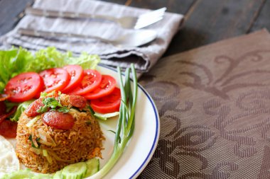 Kızarmış pilav ve Çin sosisi kızarmış yumurta, domates ve marul ile servis edilir..