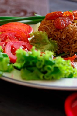 Kızarmış pilav ve Çin sosisi kızarmış yumurta, domates ve marul ile servis edilir..