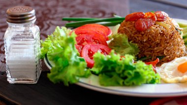 Kızarmış pilav ve Çin sosisi kızarmış yumurta, domates ve marul ile servis edilir..