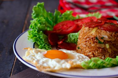 Kızarmış pilav ve Çin sosisi kızarmış yumurta, domates ve marul ile servis edilir..
