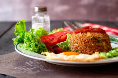 Kızarmış pilav ve Çin sosisi kızarmış yumurta, domates ve marul ile servis edilir..