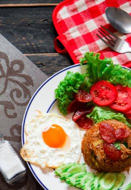 Kızarmış pilav ve Çin sosisi kızarmış yumurta, domates ve marul ile servis edilir..