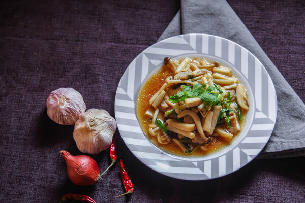 Enoki mushroom stir fry with minced pork served in a white plate on a black velvet table.