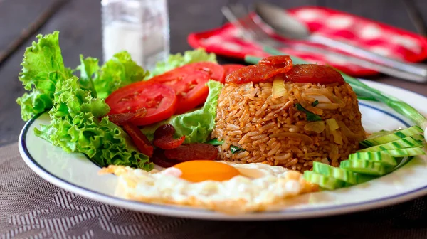 Kızarmış pilav ve Çin sosisi kızarmış yumurta, domates ve marul ile servis edilir..