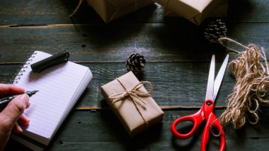 Kraft kağıdından hediye paketi sicimle sarılmış, el yapımı konsept, siyah ahşap masa üzerine yerleştirilmiş.