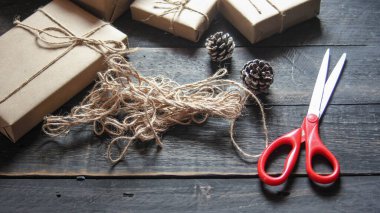 Kraft kağıdından hediye paketi sicimle sarılmış, el yapımı konsept, siyah ahşap masa üzerine yerleştirilmiş.