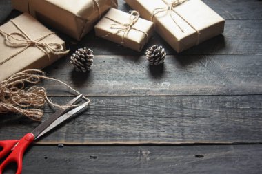 Kraft kağıdından hediye paketi sicimle sarılmış, el yapımı konsept, siyah ahşap masa üzerine yerleştirilmiş.