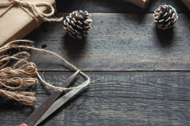 Kraft kağıdından hediye paketi sicimle sarılmış, el yapımı konsept, siyah ahşap masa üzerine yerleştirilmiş.