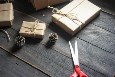 Kraft kağıdından hediye paketi sicimle sarılmış, el yapımı konsept, siyah ahşap masa üzerine yerleştirilmiş.