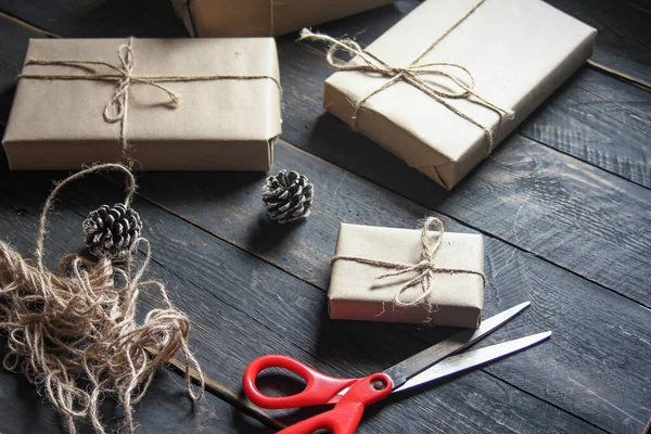 gift wrapping from Kraft paper wrapped with twine, the concept of handmade, placed on black wooden table