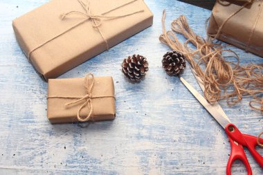 İplikle sarılmış Kraft kağıdından hediye paketi, el yapımı konsept, açık mavi masa üstü.