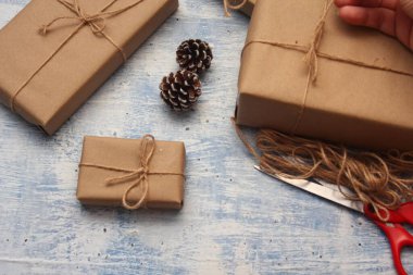 İplikle sarılmış Kraft kağıdından hediye paketi, el yapımı konsept, açık mavi masa üstü.