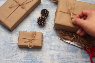 İplikle sarılmış Kraft kağıdından hediye paketi, el yapımı konsept, açık mavi masa üstü.