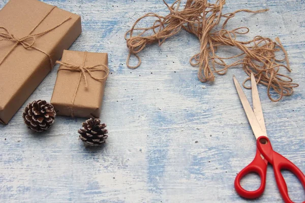 İplikle sarılmış Kraft kağıdından hediye paketi, el yapımı konsept, açık mavi masa üstü.