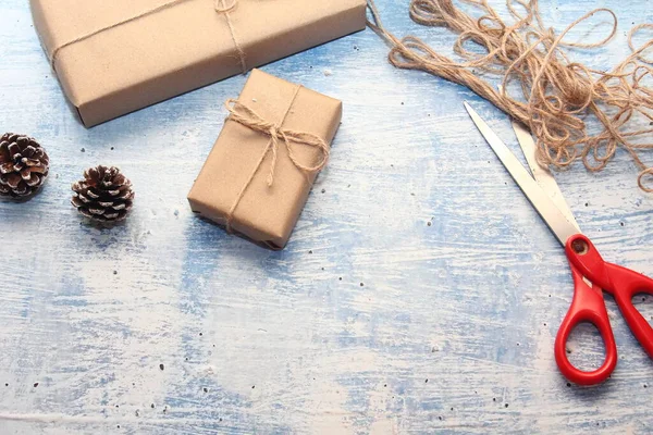 İplikle sarılmış Kraft kağıdından hediye paketi, el yapımı konsept, açık mavi masa üstü.