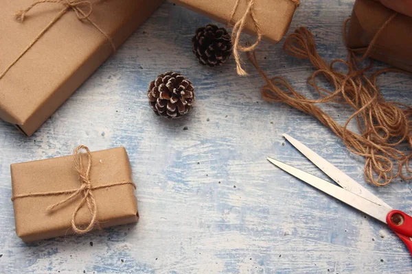 İplikle sarılmış Kraft kağıdından hediye paketi, el yapımı konsept, açık mavi masa üstü.