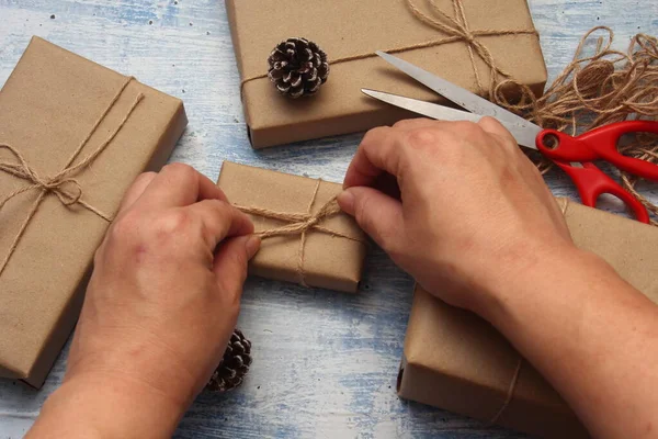 İplikle sarılmış Kraft kağıdından hediye paketi, el yapımı konsept, açık mavi masa üstü.