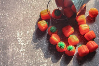 Cadılar Bayramı renkli balkabağı şekilli şeker kamışları arka planda güneş ışığı olan gri bir masanın üzerine konur..