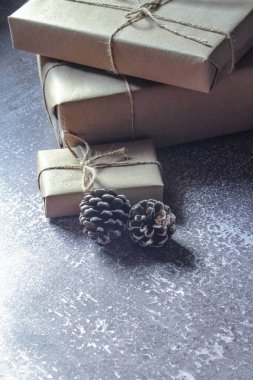 Kraft kağıdından hediye paketi, sicimle sarılmış, el yapımı konsept, gri bir masaya konur.