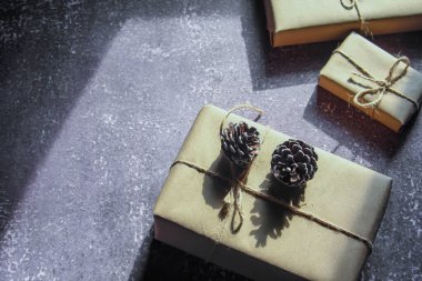 Kraft kağıdından hediye paketi, sicimle sarılmış, el yapımı konsept, gri bir masaya konur.