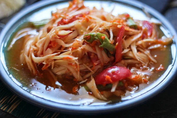 stock image Spicy papaya salad served in a blue dish with sticky rice in a bucket and long beans, dried chilli and vegetables.