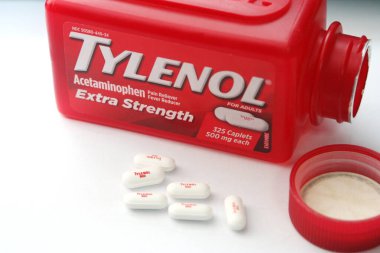 WA-AMERICA - SEP 11 2025: Kırmızı Tylenol Extra güçlü bir şişe ve el değmemiş beyaz arka planda birkaç beyaz başlık yakın çekim.