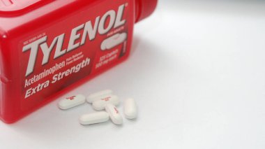 WA-AMERICA - SEP 11 2025: Kırmızı Tylenol Extra güçlü bir şişe ve el değmemiş beyaz arka planda birkaç beyaz başlık yakın çekim.