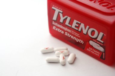 WA-AMERICA - SEP 11 2025: Kırmızı Tylenol Extra güçlü bir şişe ve el değmemiş beyaz arka planda birkaç beyaz başlık yakın çekim.