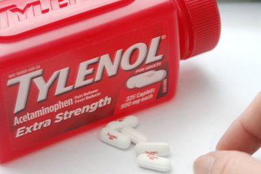 WA-AMERICA - SEP 11 2025: Kırmızı Tylenol Extra güçlü bir şişe ve el değmemiş beyaz arka planda birkaç beyaz başlık yakın çekim.