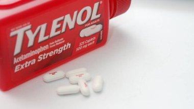 WA-AMERICA - SEP 11 2025: Kırmızı Tylenol Extra güçlü bir şişe ve el değmemiş beyaz arka planda birkaç beyaz başlık yakın çekim.