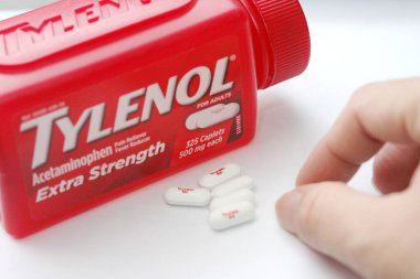 WA-AMERICA - SEP 11 2025: Kırmızı Tylenol Extra güçlü bir şişe ve el değmemiş beyaz arka planda birkaç beyaz başlık yakın çekim.