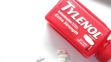 WA-AMERICA - SEP 11 2025: Kırmızı Tylenol Extra güçlü bir şişe ve el değmemiş beyaz arka planda birkaç beyaz başlık yakın çekim.