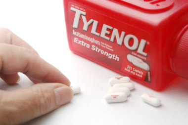 WA-AMERICA - SEP 11 2025: Kırmızı Tylenol Extra güçlü bir şişe ve el değmemiş beyaz arka planda birkaç beyaz başlık yakın çekim.