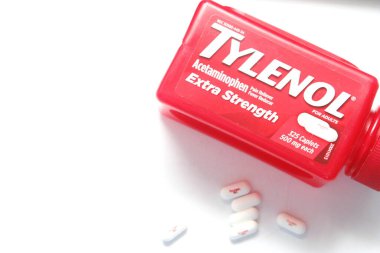 WA-AMERICA - SEP 11 2025: Kırmızı Tylenol Extra güçlü bir şişe ve el değmemiş beyaz arka planda birkaç beyaz başlık yakın çekim.