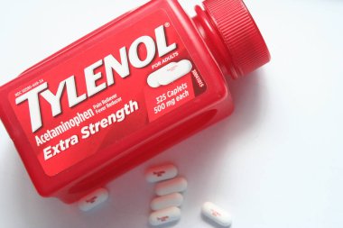 WA-AMERICA - SEP 11 2025: Kırmızı Tylenol Extra güçlü bir şişe ve el değmemiş beyaz arka planda birkaç beyaz başlık yakın çekim.