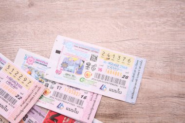 Bangkok, Tayland 18 Haziran 2025, Tayland piyango biletlerinin bir koleksiyonu ahşap bir yüzeyde, renkli tasarımlar sergileniyor, seri numaraları ve bilgi çekiliyor.