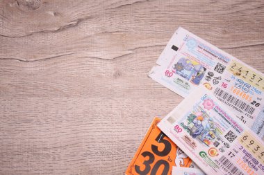 Bangkok, Tayland 18 Haziran 2025, Tayland piyango biletlerinin bir koleksiyonu ahşap bir yüzeyde, renkli tasarımlar sergileniyor, seri numaraları ve bilgi çekiliyor.