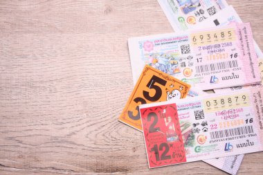 Bangkok, Tayland 18 Haziran 2025, Tayland piyango biletlerinin bir koleksiyonu ahşap bir yüzeyde, renkli tasarımlar sergileniyor, seri numaraları ve bilgi çekiliyor.