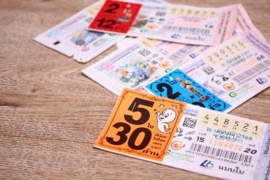 Bangkok, Tayland 18 Haziran 2025, Tayland piyango biletlerinin bir koleksiyonu ahşap bir yüzeyde, renkli tasarımlar sergileniyor, seri numaraları ve bilgi çekiliyor.