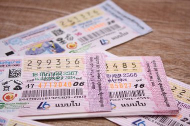 Bangkok, Tayland 18 Haziran 2025, Tayland piyango biletlerinin bir koleksiyonu ahşap bir yüzeyde, renkli tasarımlar sergileniyor, seri numaraları ve bilgi çekiliyor.