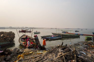 Varanasi, Inde - 03 19 2024: Manikarnika ghat 'taki işçilerin önündeki köpek Asya, Hindistan, Uttar Pradesh, Varanasi, yaz mevsiminde, güneşli bir günde. .