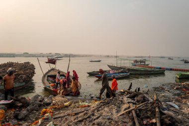 Varanasi, Inde - 03 19 2024: Manikarnika ghat 'taki işçilerin önündeki köpek Asya, Hindistan, Uttar Pradesh, Varanasi, yaz mevsiminde, güneşli bir günde. .