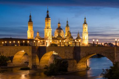 Zaragoza, Espagne - 05: 11: 2024: Güneşli bir günde, Zaragoza, İspanya, Aragon, Zaragoza 'da, geceleyin Sütunun Hanımefendisinin Bazilikası ve Taş Köprüsü. .