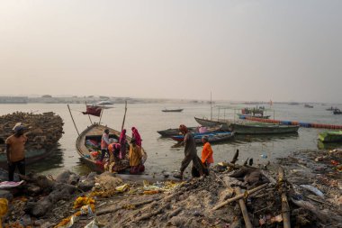 Varanasi, Inde - 03 19 2024: Manikarnika ghat 'taki işçilerin önündeki köpek Asya, Hindistan, Uttar Pradesh, Varanasi, yaz mevsiminde, güneşli bir günde. .