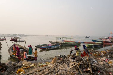 Varanasi, Inde - 03 19 2024: Manikarnika ghat 'taki işçilerin önündeki köpek Asya, Hindistan, Uttar Pradesh, Varanasi, yaz mevsiminde, güneşli bir günde. .